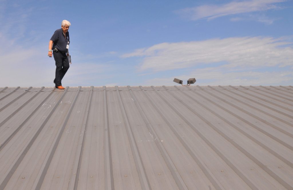 Professional roofing contractor inspecting a home's roof for storm damage.