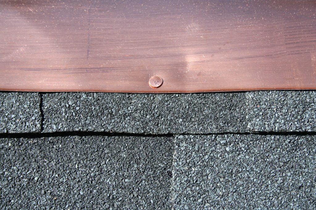 Loose roof flashing around a chimney after a storm.