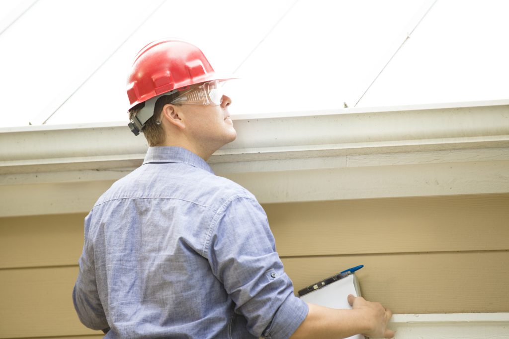 Inspector Or Blue Collar Worker Examines Building Roof Outdoors